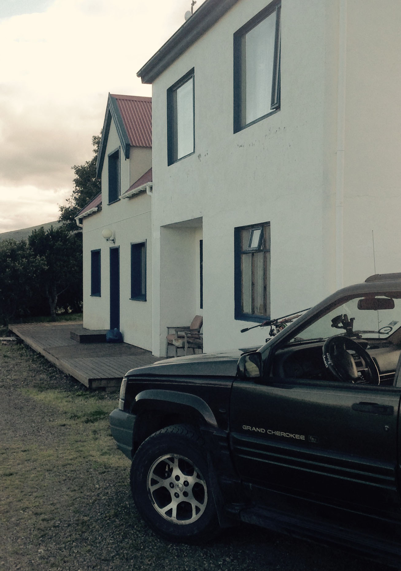 Voiture avec cannes à pêche, maison blanche en arrière plan