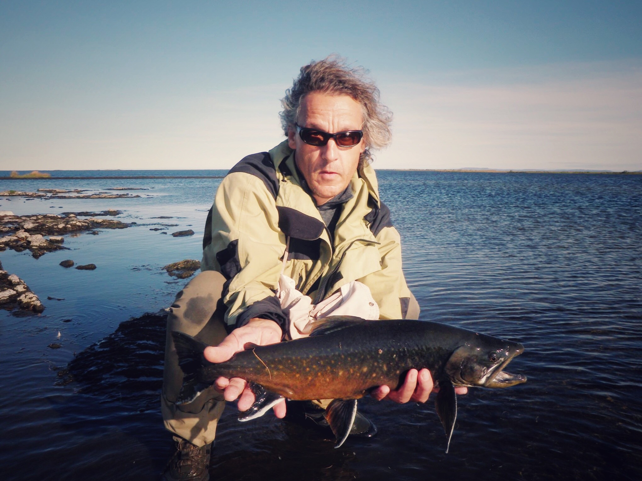 Plaine du renard polaire Homme tenant un poisson près d'un lac dans la plaine du renard polaire en Islande