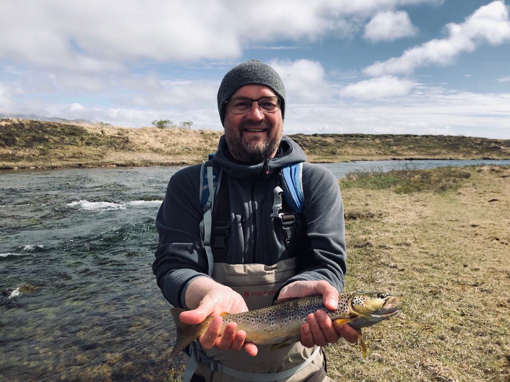 homme tenant une truite dans les mains, lors d'un voyage de pêche dans les perles du sud en islande