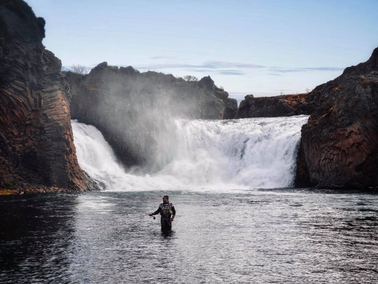 cascade en islande, homme situé dans l'eau qui pêche le saumon à la mouche.