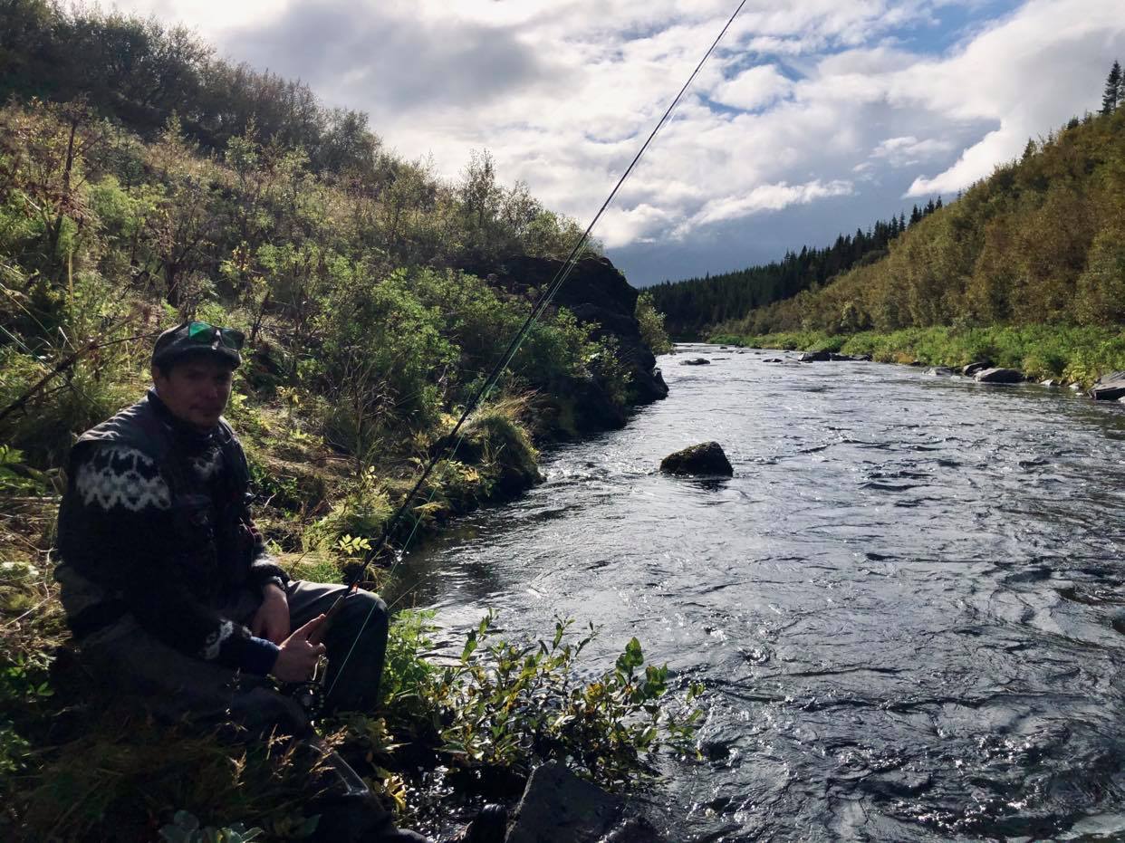 Pêcheur assis au bord d'une rivière à saumon en Islande