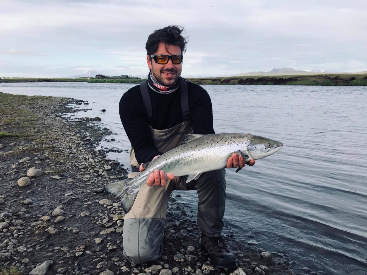 homme tenant un saumon atlantique en islande