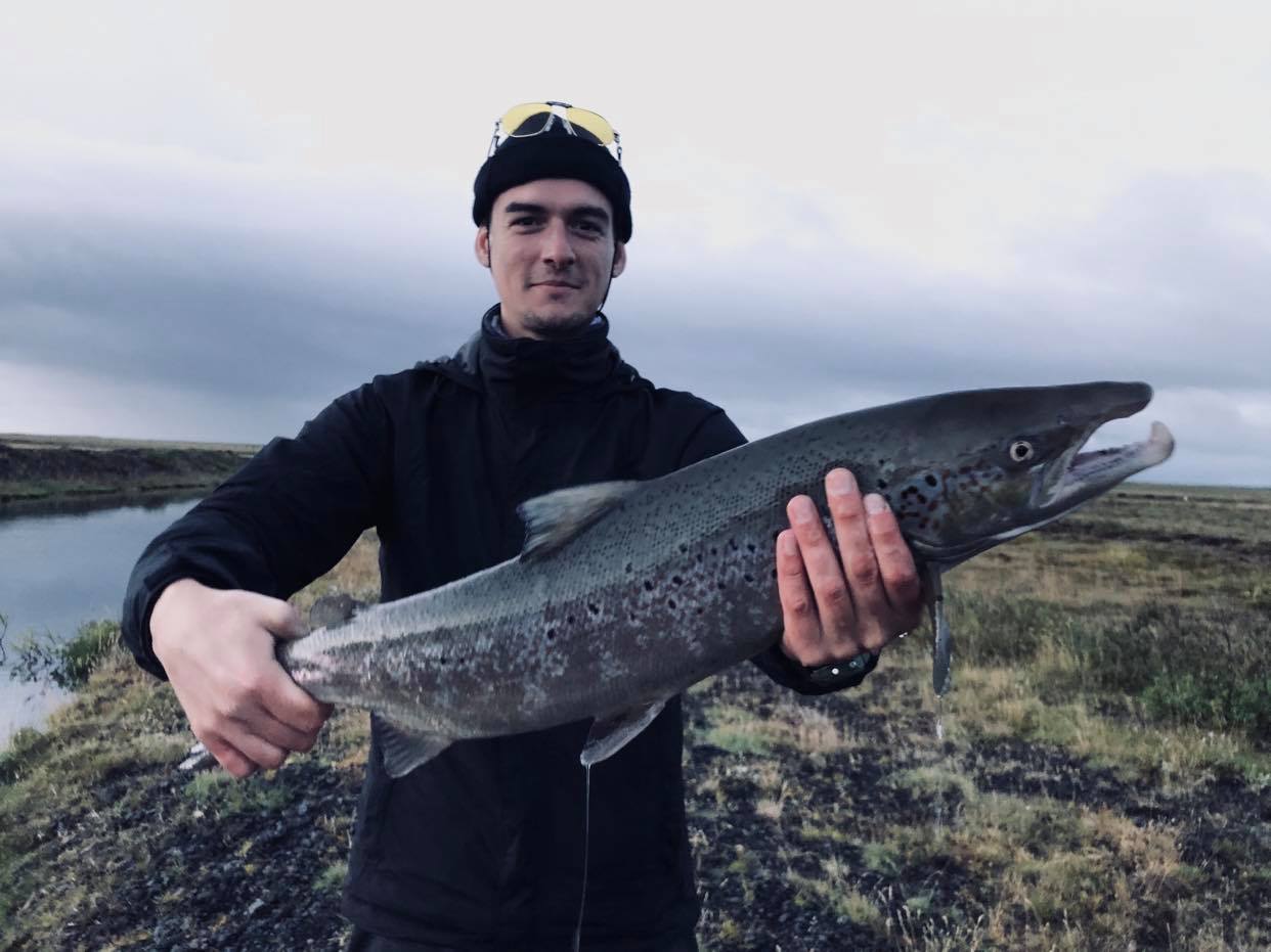 homme tenant un saumon atlantique en islande