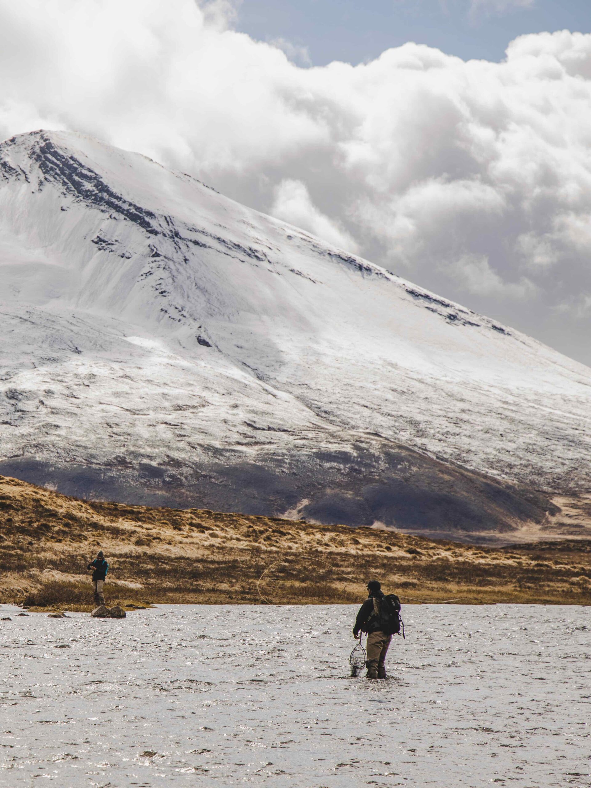 Deux pêcheurs à la mouche dans une rivière en Islande, avec une montagne enneigée à l'arrière plan